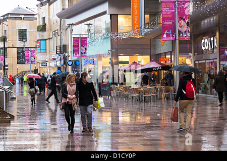 Gli amanti dello shopping sotto la pioggia in una zona pedonale del centro di Cardiff, Galles, Regno Unito Foto Stock