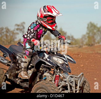 Bambino - di età compresa tra i quattro - su quad bike indossando un abbigliamento protettivo e cavalcare su sterrato Foto Stock