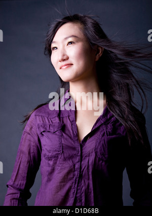 Donna asiatica con capelli lunghi soffiando Foto Stock