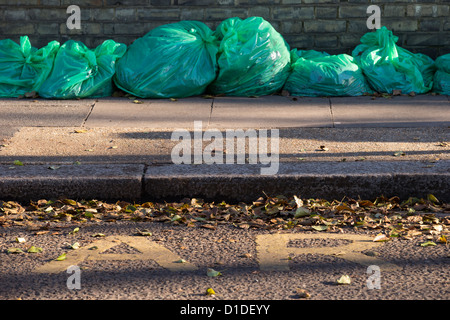 Green sacchi per i rifiuti alimentato da Hounslow consiglio e riempito con foglie di autunno allineati pronti per la raccolta Foto Stock