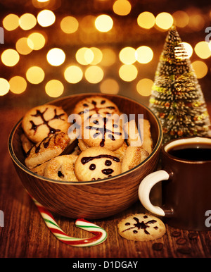 Foto di Natale gingerbread con tazza di caffè sul tavolo di legno, Nuovo Anno dolci ancora in vita su scuro dello sfondo incandescente Foto Stock