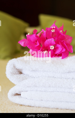 Asciugamani Bianchi con fiori su un letto in una camera di hotel. Messa a fuoco selettiva su fiori. Foto Stock