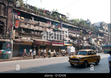 Giallo taxi Kolkata passando Kolkata baraccopoli nelle prime ore del mattino, Calcutta, West Bengal, India, Asia Foto Stock