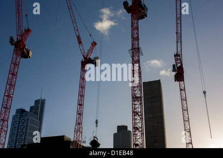 Gru e cielo blu su un grande sito di costruzione a Broadgate sviluppo nella City di Londra. Guardando verso l'alto da un angolo basso, vediamo solo due nuvole in una altrimenti cielo blu, con quattro del progetto raggiungendo gru verso l'alto, il cemento armato albero di sollevamento di un nuovo edificio in rapida crescita e il completamento di un blocco sulla sinistra. Broadgate è un grande, 32 acri (13 ha) office e retail station wagon nella City di Londra, di proprietà di terra britannica e il Gruppo Blackstone e gestito da Broadgate Estates. Lo sviluppatore originale era Rosehaugh: è stato costruito da un Bovis / Tarmac Construction joint venture Foto Stock