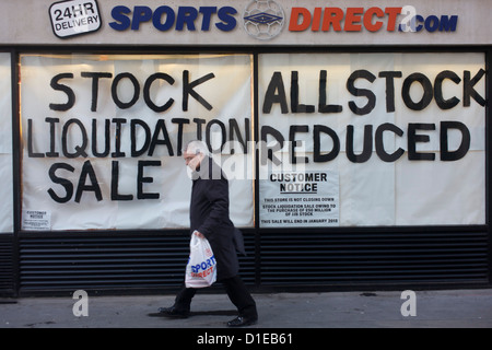 An all reduced sale of sports clothing supplier JJB.com stock, being sold by new buyer, Sports Direct shop in central London. A male shopper walks past the store window with a Sports Direct bag, passing the large lettering painted onto the glass, declaring the stock sale.  JJB Sports has collapsed into administration, with arch-rival Sports Direct acquiring 20 stores. KPMG partners Brian Green, David Costley-Wood and Richard Fleming were appointed administrators before Sports Direct bought the JJB assets for £23.77m. Foto Stock