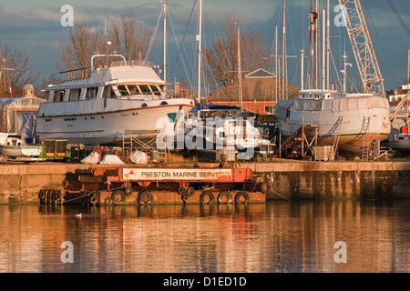 Riscaldare il tardo autunno sole bagna le barche in cantiere a Preston Docks, Lancashire, Inghilterra Foto Stock