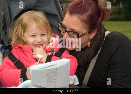 Madre con sua figlia di 3 anni a un esterno di canti di natale evento al tempo di Natale, Farnham, Surrey, Regno Unito. Foto Stock