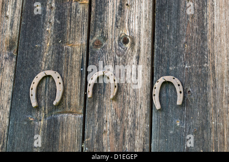 Retrò rusty Ferri da cavallo appendere su chiodi in legno vecchio casa rurale parete. Foto Stock