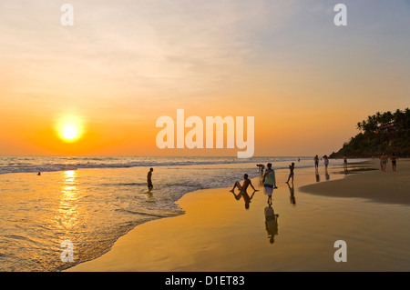 Vista orizzontale di persone rilassante e guardare il tramonto sulla spiaggia di Papanasam in Varkala, Kerala. Foto Stock