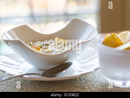 Hot porridge di fiocchi d'avena o porage avena in bianco ceramica moderna vaschetta sul tavolo per la colazione Foto Stock