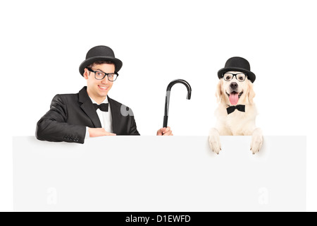 Un musicista in tuta, retrò hat e della canna da zucchero in posa con il cane dietro un pannello isolato su bianco Foto Stock