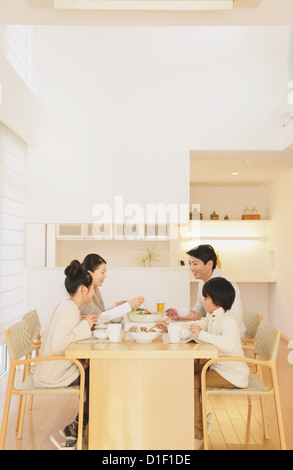 Una famiglia di quattro persone di mangiare al tavolo da pranzo in soggiorno Foto Stock