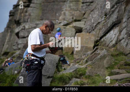 Lettura maschio una scalata su roccia prenota /guida in piedi al di sotto del bordo Stanage nel distretto di Peak Derbyshire Inghilterra Foto Stock