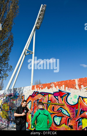 Irroratrici giovani dipinto graffiti sui resti del muro di Berlino nel Parco del Muro di Berlino in Germania Foto Stock