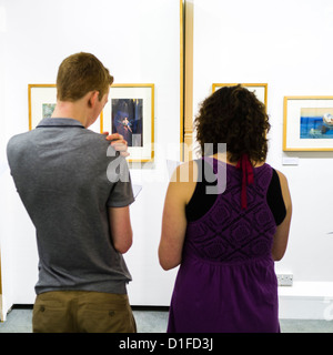 Aberystwyth University School of Art, vista posteriore di due studenti esaminando e discutendo i dipinti in una galleria, Wales UK Foto Stock