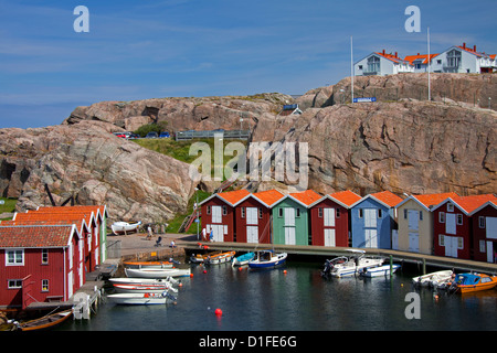 Colorate di pesca tradizionali capanne e boathouses con barche lungo il molo in legno a Smögen, Bohuslän, Svezia e Scandinavia Foto Stock