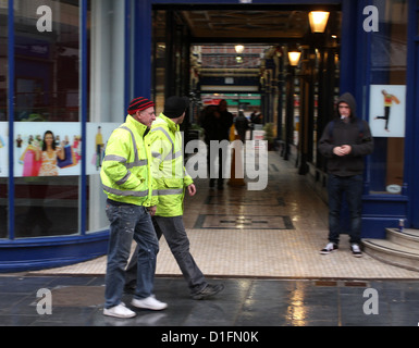 Due uomini di lavoro in alta viz cappotti a piedi attraverso il centro di Newport Gwent nel Galles del Sud, Dicembre 2012 Foto Stock