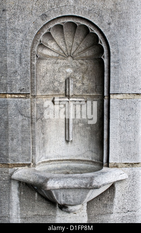 Una croce e acqua santa ben come parte dell'architettura di una cattedrale Foto Stock