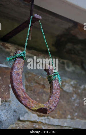 Un vecchio, arrugginiti, a ferro di cavallo appeso per fortuna dal cornicione di una casa. Foto Stock