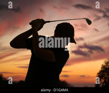 Il Golfer oscillazione un Golf Club stagliano contro un Cielo di tramonto. Close up. Foto Stock