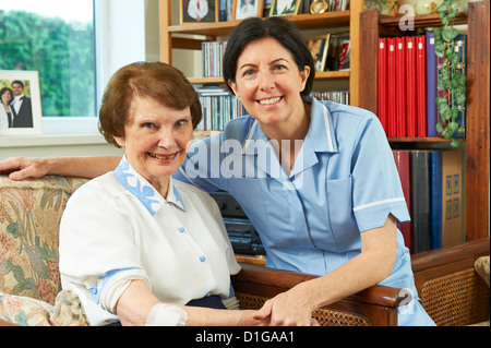 Lavoratore di cura di salute di medicazione sulla ferita un senior womans arm a casa Foto Stock