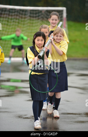 Gli scolari che trasportano un netball obiettivo a Nostra Signora & San Werburgh Cattolico della scuola primaria a Newcastle-under-Lyme, Staffordshi Foto Stock