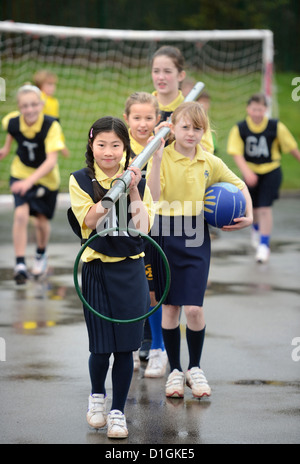 Gli scolari che trasportano un netball obiettivo a Nostra Signora & San Werburgh Cattolico della scuola primaria a Newcastle-under-Lyme, Staffordshi Foto Stock