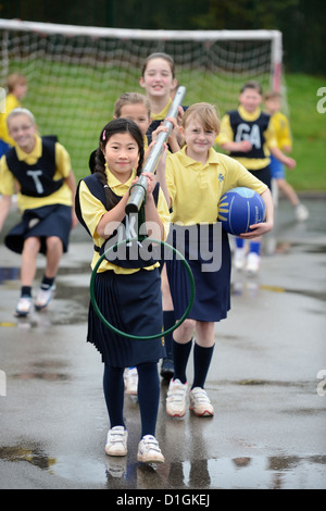 Gli scolari che trasportano un netball obiettivo a Nostra Signora & San Werburgh Cattolico della scuola primaria a Newcastle-under-Lyme, Staffordshi Foto Stock