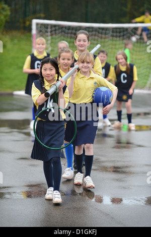 Gli scolari che trasportano un netball obiettivo a Nostra Signora & San Werburgh Cattolico della scuola primaria a Newcastle-under-Lyme, Staffordshi Foto Stock