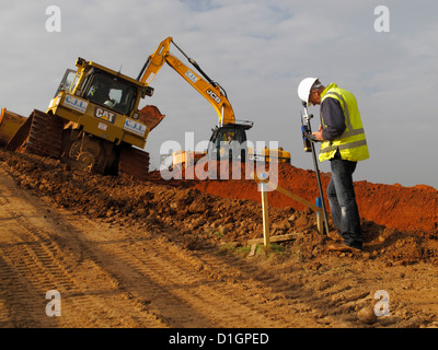 Geometra Impostazione controlli di ingegnere ferroviario di pastella peg sul Regno Unito la costruzione di nuove strade cantiere indossano alta visibilità vis vest jacket Foto Stock