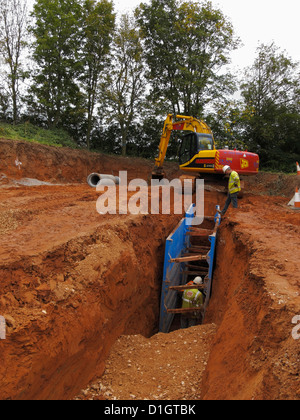 Gli uomini che lavorano in trincea profonda scavo sotto la protezione di puntellamento idraulico sistema di sostegno Regno Unito Foto Stock