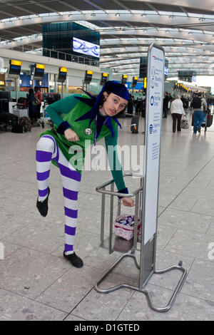 21 dicembre 2012. T5 L'aeroporto di Heathrow di Londra. Un attore vestito in un costume di elf per intrattenere i viaggiatori, su ciò che è stato previsto per essere il giorno di punta per il Natale Viaggio. © Danny Callcut Foto Stock