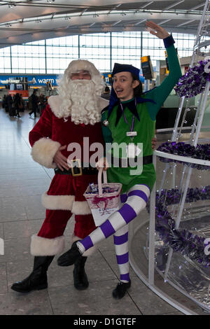 21 dicembre 2012. T5 L'aeroporto di Heathrow di Londra. Attori travestiti in Santa e elf costumi per intrattenere i viaggiatori, su ciò che è stato previsto per essere il giorno di punta per il Natale Viaggio. © Danny Callcut Foto Stock