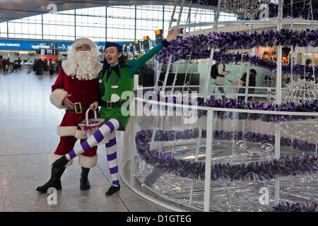 21 dicembre 2012. T5 L'aeroporto di Heathrow di Londra. Attori travestiti in Santa e elf costumi per intrattenere i viaggiatori, su ciò che è stato previsto per essere il giorno di punta per il Natale Viaggio. © Danny Callcut Foto Stock