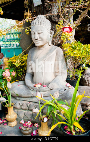 Stone statua del Buddha coperto di fiori presso il Palazzo Reale di Phnom Penh, Cambogia, Indocina, Asia sud-orientale, Asia Foto Stock