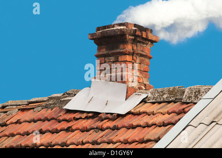 Vecchia tubazione dal forno sul tetto fuori le assicelle, sul cielo blu sullo sfondo Foto Stock