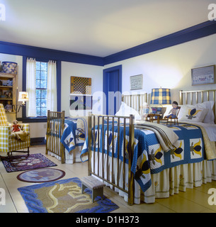 Camere da letto camera dei bambini in stile country matching trapunte su letti singoli giallo e blu colore tema letti di ottone verniciato ampia plank Foto Stock