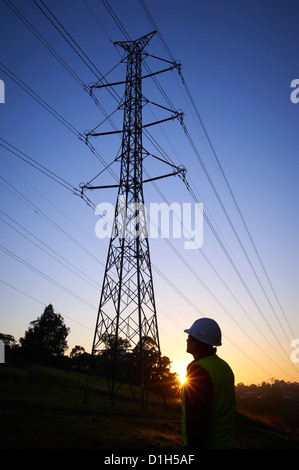 Stagliano elettricità tralicci e lavoratore in hard hat Foto Stock