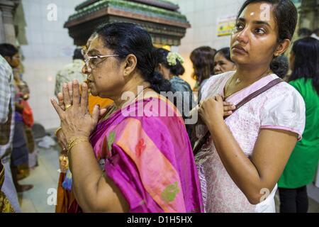 Dic. 22, 2012 - Singapore, Singapore - Donne pregare presso Sri Veeramakaliamman tempio, un tempio indù si trova in Little India di Singapore. La Sri Veeramakaliamman tempio dedicato alla dea Indù Kali, feroci di realizzazione di Shakti e il dio Shiva la moglie Parvati. Kali è sempre stata popolare nel Bengala, il luogo di nascita di gli operai che hanno costruito questo tempio nel 1881. Immagini di Kali entro il tempio mostra indossando una ghirlanda di teschi e strappando gli interni delle sue vittime e Kali la condivisione più tranquilli momenti di famiglia con i suoi figli Ganesha e Murugan. L'edificio è costruito in t Foto Stock