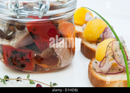 Aringhe in salamoia in un vasetto di vetro con crostini di patate Foto Stock