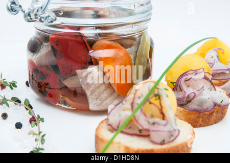 Aringhe in salamoia in un vasetto di vetro con crostini di patate Foto Stock