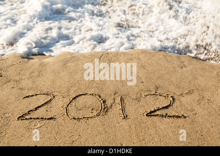 Concetto di calendario del 2012 scritto nella sabbia sulla spiaggia essendo coperte da surf e onde Foto Stock