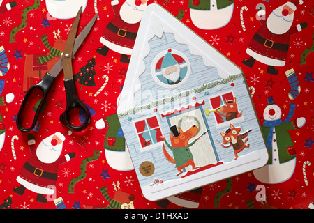 Biscotto decorativo stagno in forma di casa con carta natalizia e forbici - tenetevi pronti per avvolgere il regalo di Natale Foto Stock
