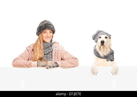Una femmina sorridente in posa con labrador retriever cane dietro un pannello vuoto Foto Stock