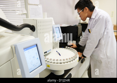 Un lavoratore di laboratorio analizza i risultati di un test di agitatore di tubo Foto Stock