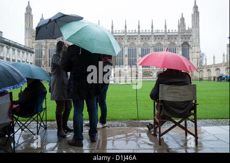 Kings College di Cambridge Regno Unito 24 dicembre 2012. Coda di folle in pioggia per i biglietti per il Festival di nove lezioni e canti natalizi svoltasi nella famosa cappella alla vigilia di Natale. Alcune persone si accamparono durante la notte e altri sono arrivati a 4.30am per assicurarsi un posto nella coda. Il concerto è trasmesso in tutto il mondo. Il meteo non hanno scoraggiato la gente gli spiriti. Foto Stock