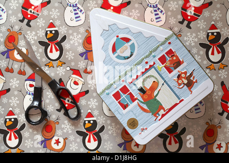 Biscotto decorativo stagno in forma di casa con carta natalizia e forbici - tenetevi pronti per avvolgere il regalo di Natale Foto Stock