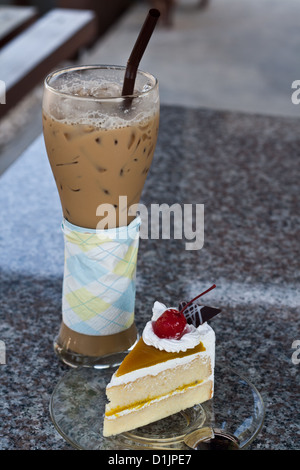 Caffè ghiacciato con cannuccia e Mango torta con ciliegie. Foto Stock