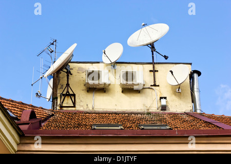 Tetto di tegole di una vecchia città europea con la produzione di massa di aria condizionata e antenna satellitare contro il cielo blu. Progr Foto Stock