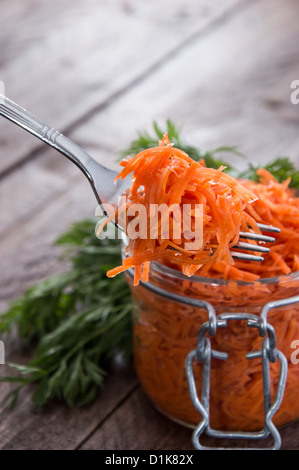 Forcella con Insalata di carote davanti a un bicchiere Foto Stock